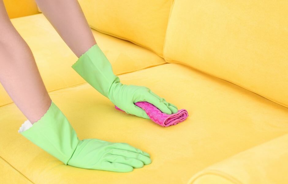 Upholstery Stain Removal Basics featured image of a yellow couch being wiped down.